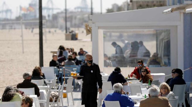 Un camarero atiende las mesas de una terraza en uno de los restaurantes de la playa de la Malvarrosa de Valencia