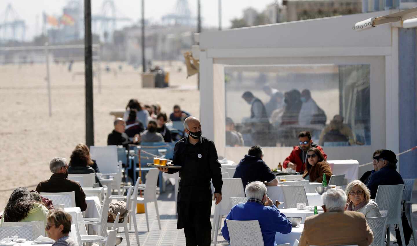 Un camarero atiende las mesas de una terraza en uno de los restaurantes de la playa de la Malvarrosa de Valencia