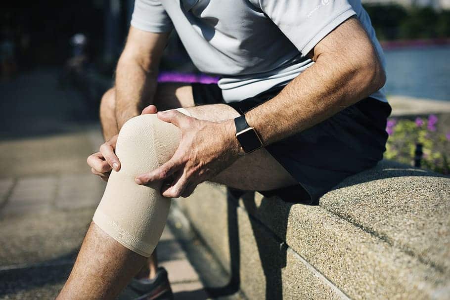 Un hombre con una rodillera sufriendo de dolor en la articulación