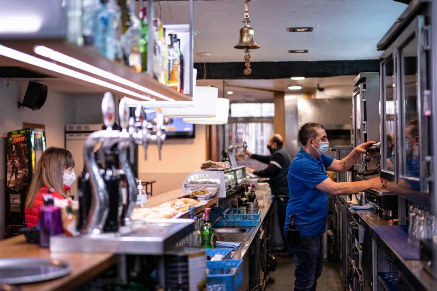 Un trabajador prepara un café en un bar.