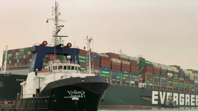 Un remolcador pasa junto al buque portacontenedores llamado Ever Given, operado por Evergreen Marine, encallado en el Canal de Suez.