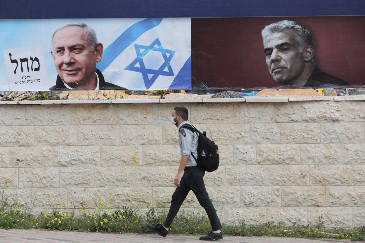 Un israelí pasa cerca de dos carteles electorales, uno de ellos de Netanyahu