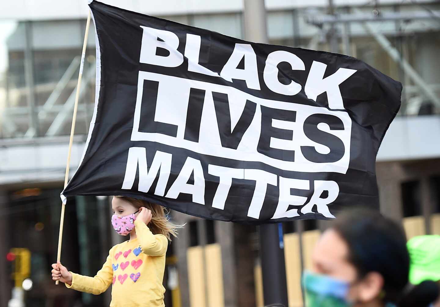 Una niña porta una bandera que dice 'las vidas de los negros importan" en Minneapolis