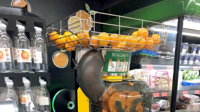 Máquina de zumo de naranja junto a las botellas en Mercadona.