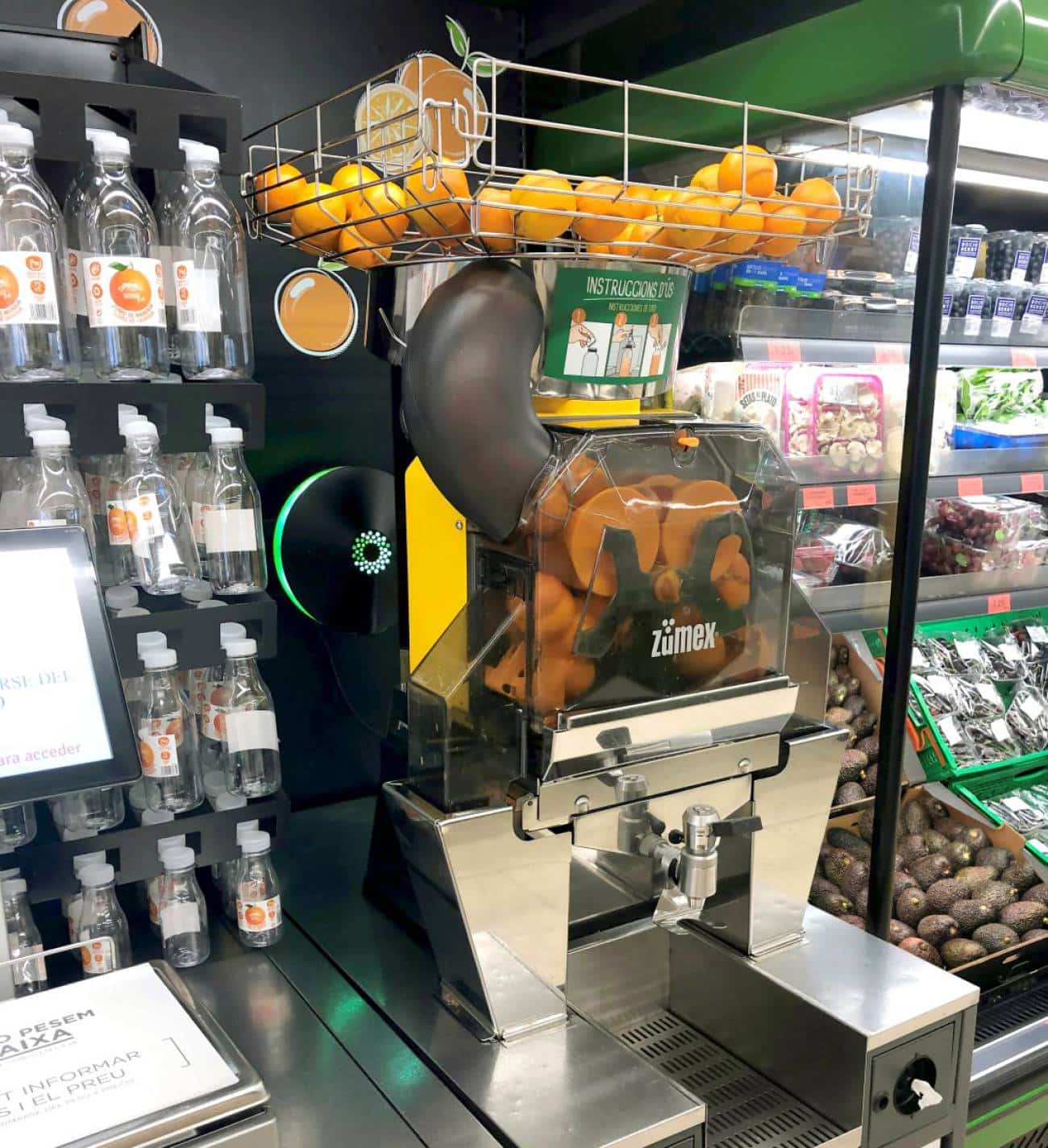 Máquina de zumo de naranja junto a las botellas en Mercadona.