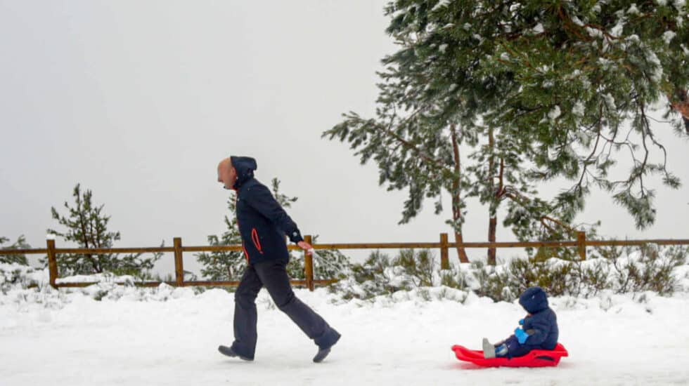Un padre tira del trineo de su hijo durante el temporal de nieve en la Sierra de Madrid, en el Puerto de Navacerrada