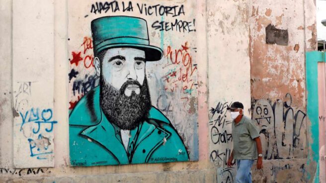 Un cubano pasa cerca de un dibujo de Fidel Castro con uno de sus lemas