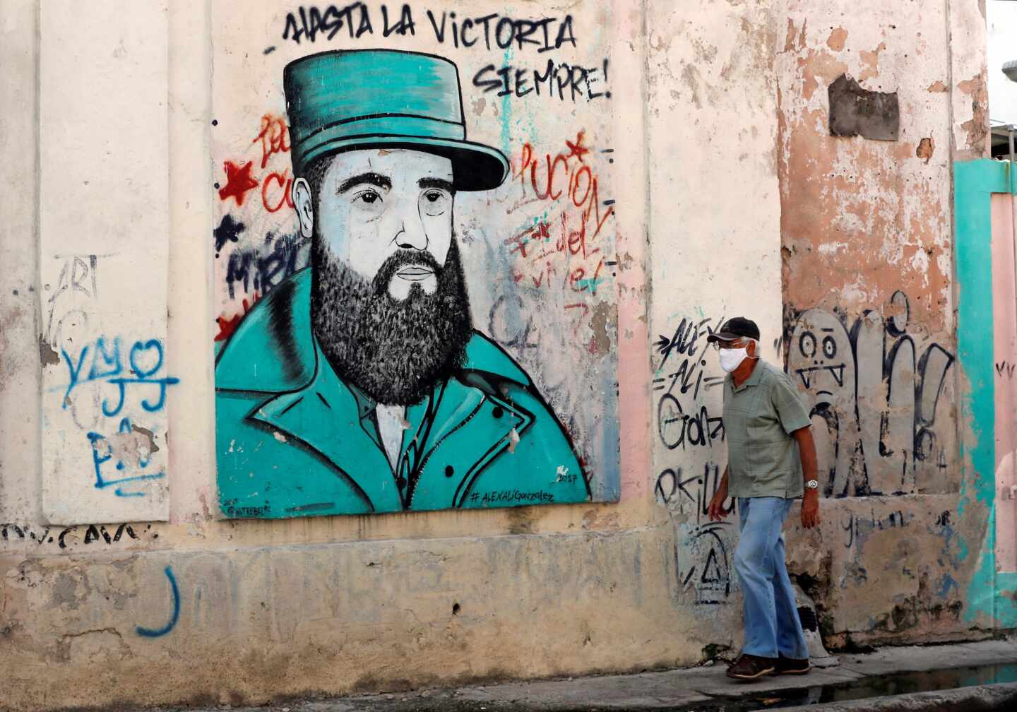 Un cubano pasa cerca de un dibujo de Fidel Castro con uno de sus lemas