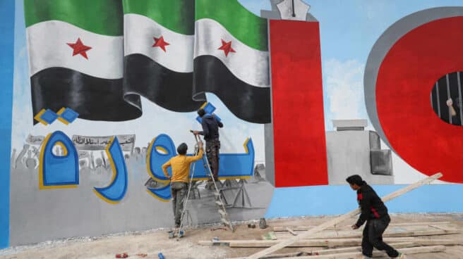 Unos jóvenes pintan un muro con la palabra 'Revolución' en árabe en Idlib, Siria