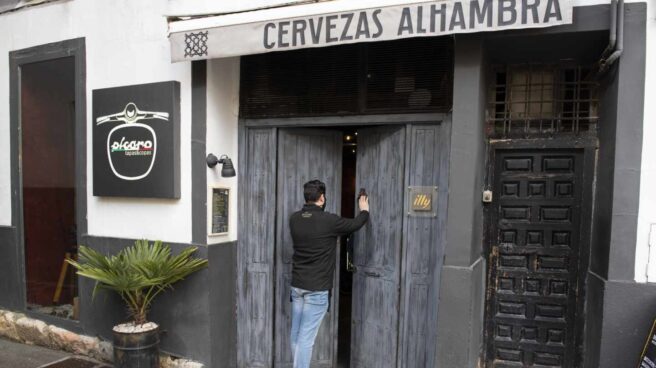 Un hombre abre la puerta de un bar cerrado.