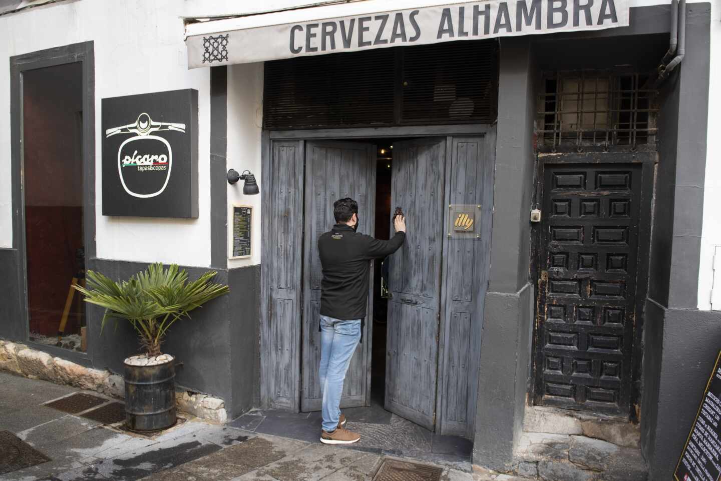 Un hombre abre la puerta de un bar cerrado.