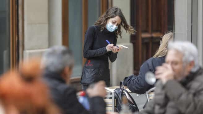 Una camarera atiende a varios clientes en una terraza