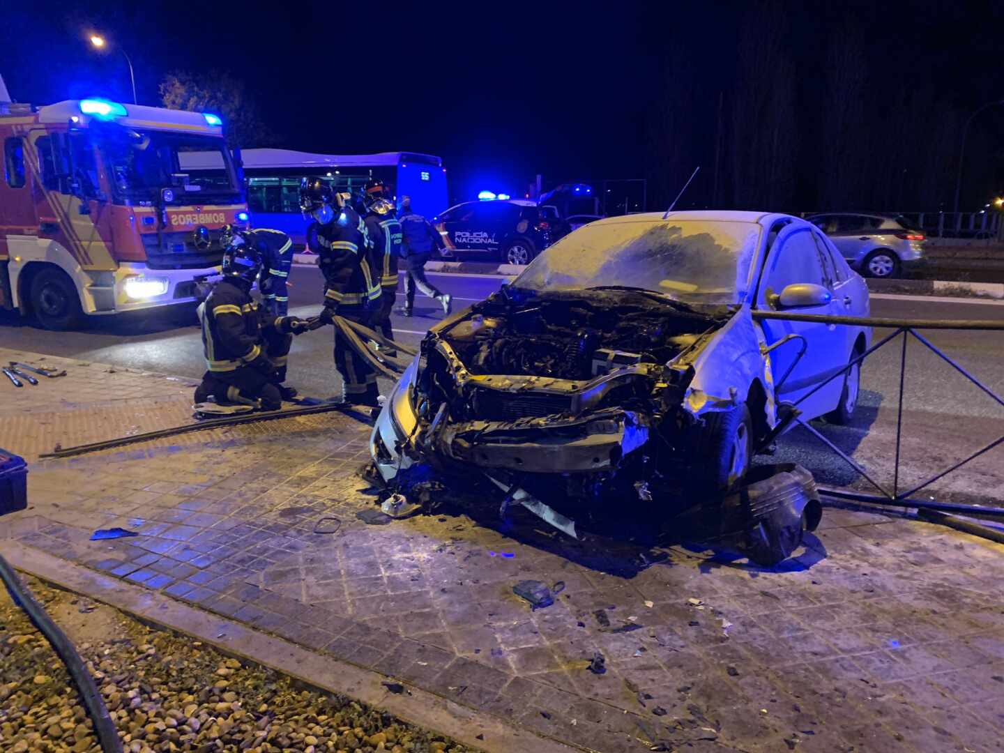 Los bomberos junto al vehículo calcinado