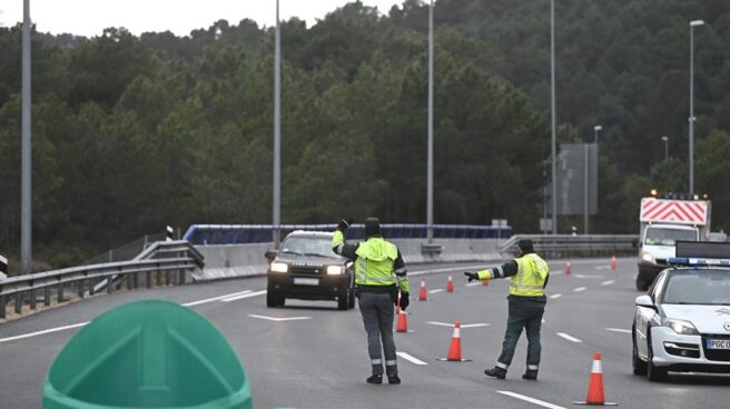 Agentes de la Guardia Civil dan el alto a un vehículo en un control en la AP-6 sobre el cierre perimetral.