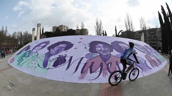 Un ciclista pasa ante el mural feminista al aire libre situado en el paseo de Pastrana de Alcalá de Henares