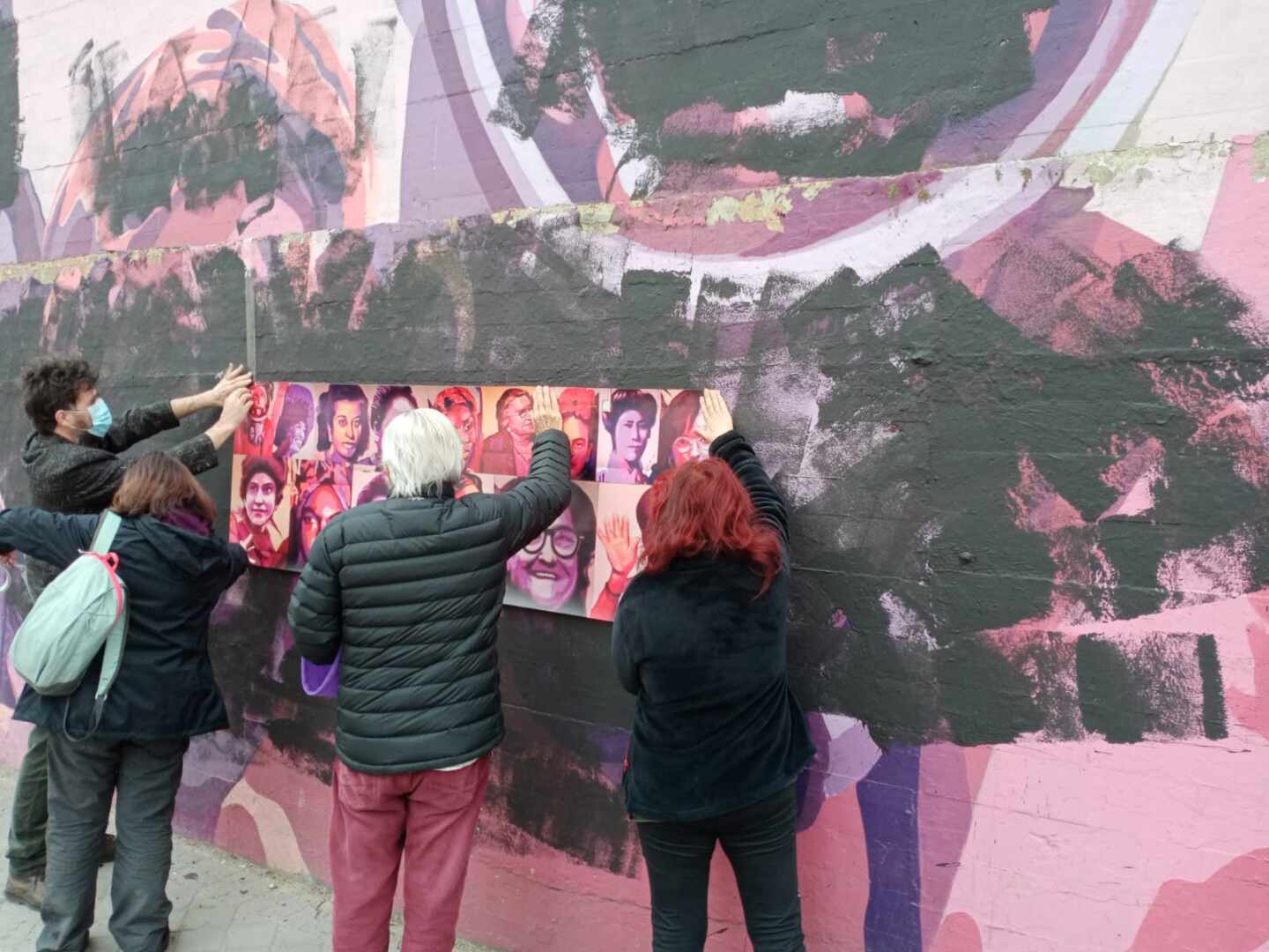 Varios vecinos colocan rostros de mujeres sobre el mural vandalizado de Ciudad Lineal.