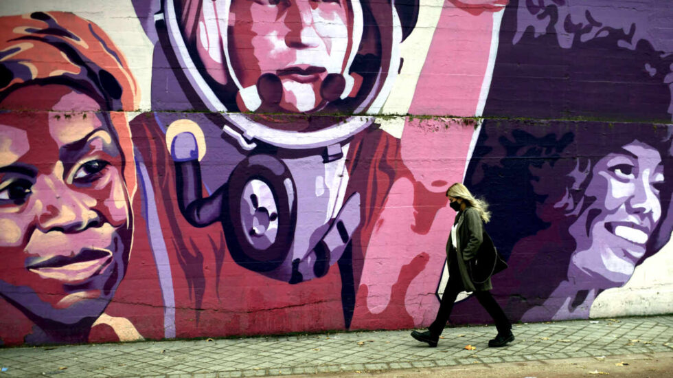 Una mujer pasa por el mural feminista en el polideportivo municipal de la Concepción en el distrito de Ciudad Lineal (Madrid).