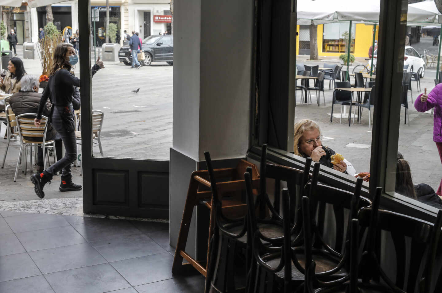 Imagen de un bar con mesas recogidas en el interior y con la terraza abierta.