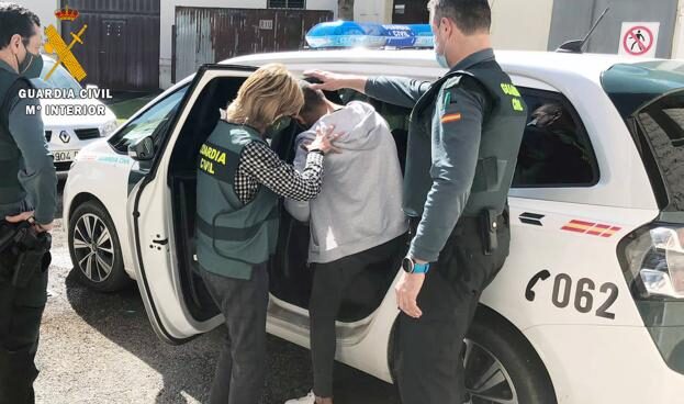 Uno de los detenidos entrando esposado al vehículo de la Guardia Civil