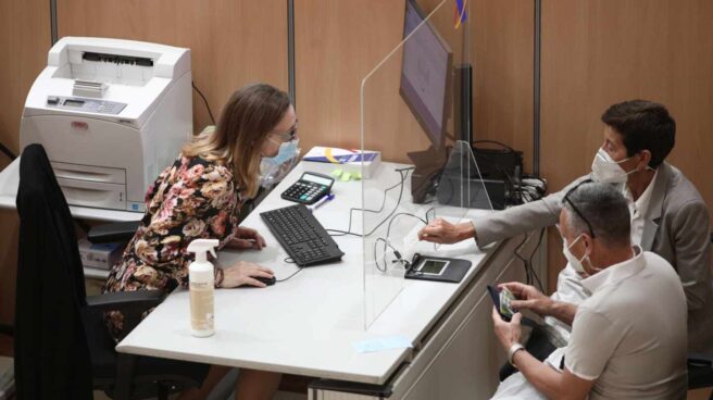 Una trabajadora de una oficina de la Agencia Tributaria en Madrid atiende a dos contribuyentes.