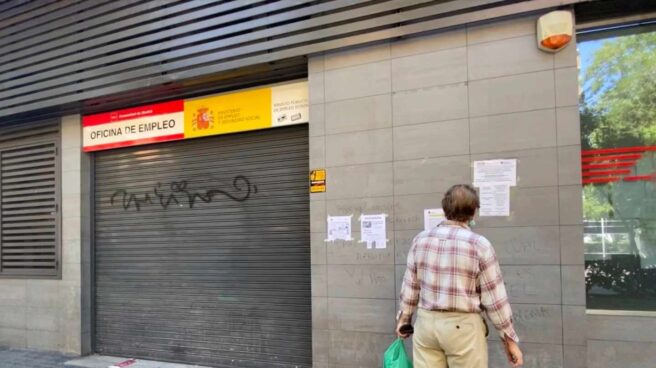 Una persona observa uno de los carteles con instrucciones para hacer trámites por internet colocados en la fachada de una oficina del SEPE.