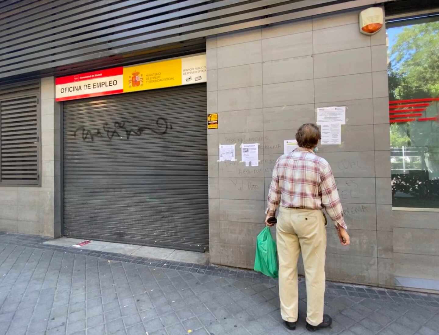 Una persona observa uno de los carteles con instrucciones para hacer trámites por internet colocados en la fachada de una oficina del SEPE.