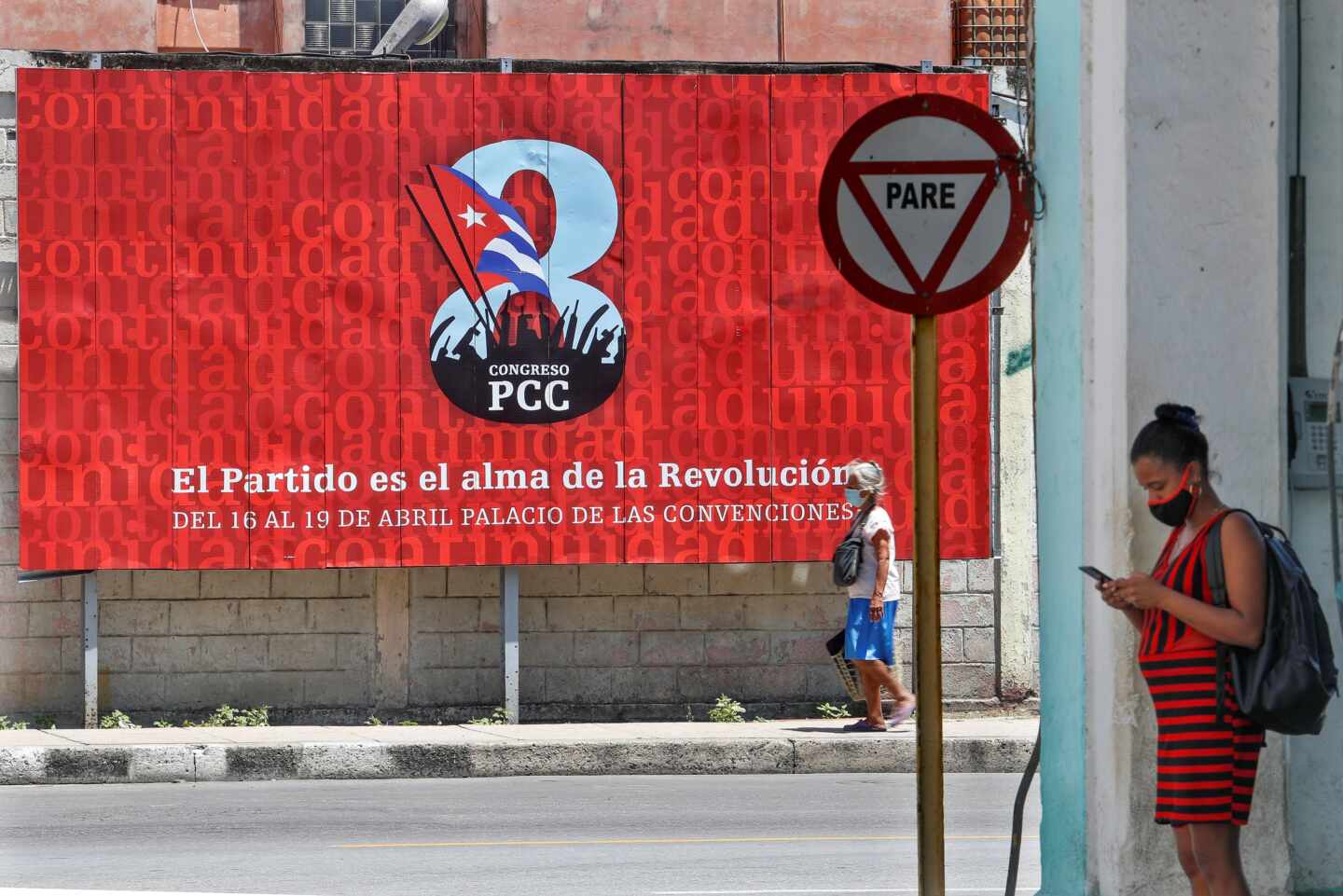 Una cubana consulta el móvil ante un cartel sobre el VIII Congreso del Partido Comunista de Cuba