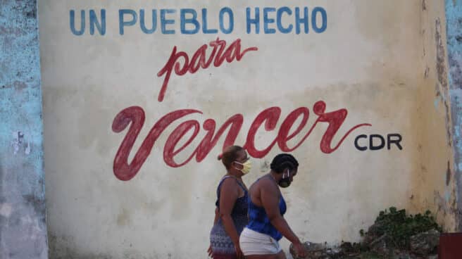 Se acabó o cómo caen los regímenes colectivistas Dos cubanas pasan debajo de un lema castrista en La Habana