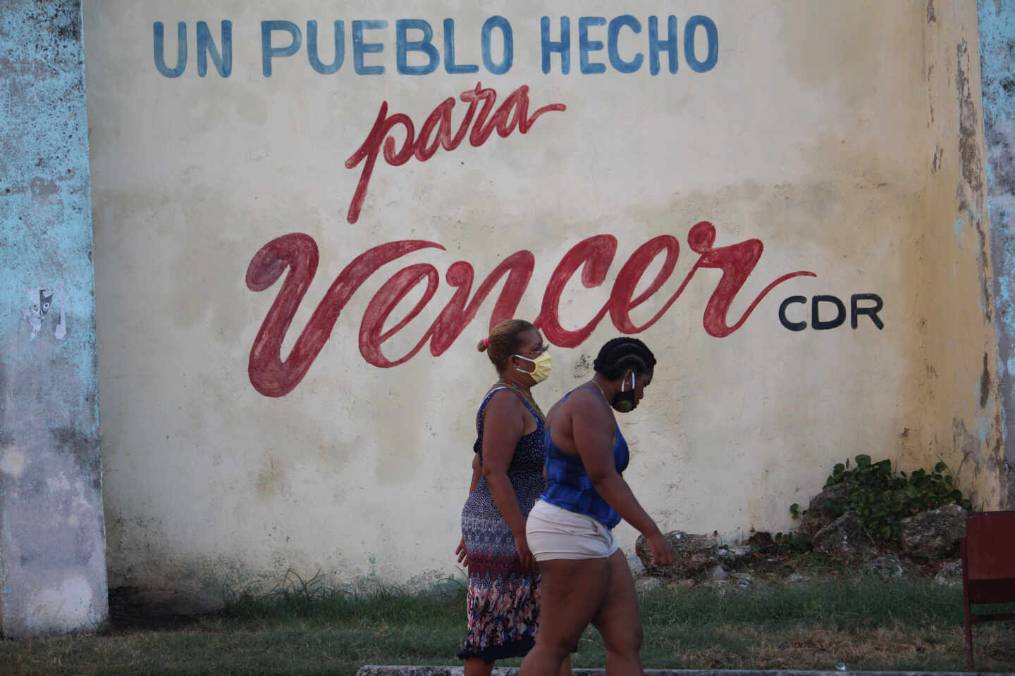Dos cubanas pasan debajo de un lema castrista en La Habana