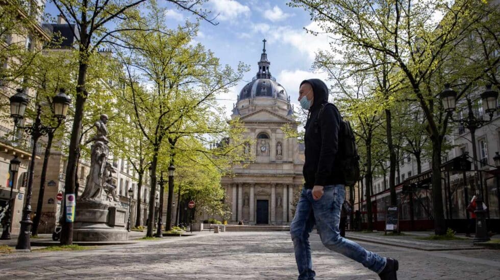 Un hombre camina delante de la Universidad de la Sorbona en París