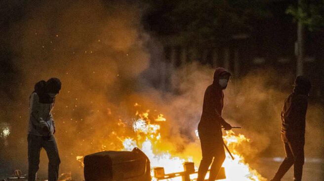 Un grupo de jóvenes contempla cómo arden objetos tras una noche de disturbios en el Ulster