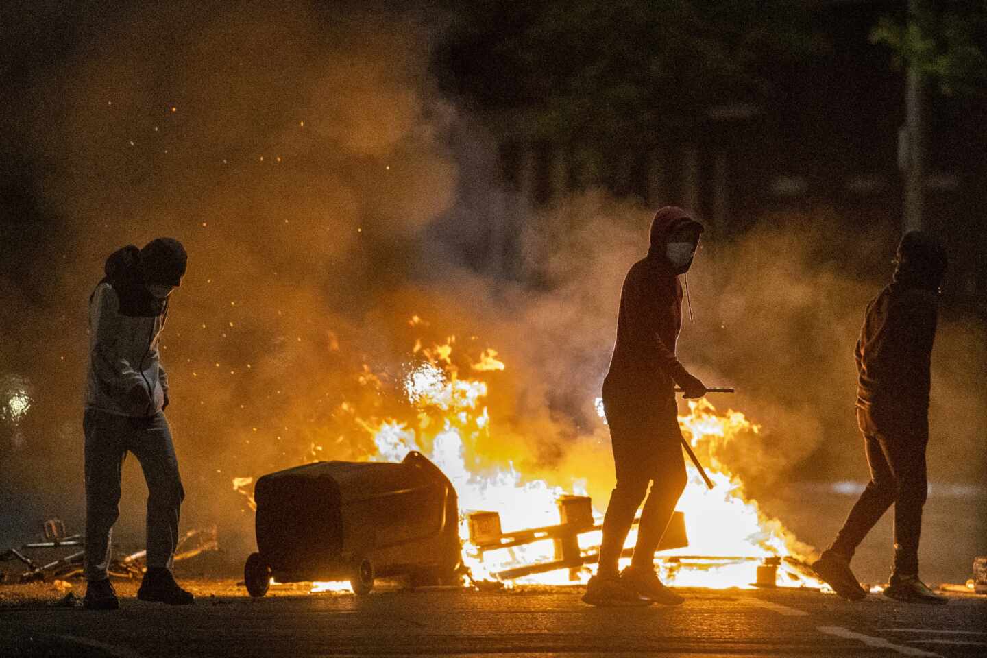 Un grupo de jóvenes contempla cómo arden objetos tras una noche de disturbios en el Ulster