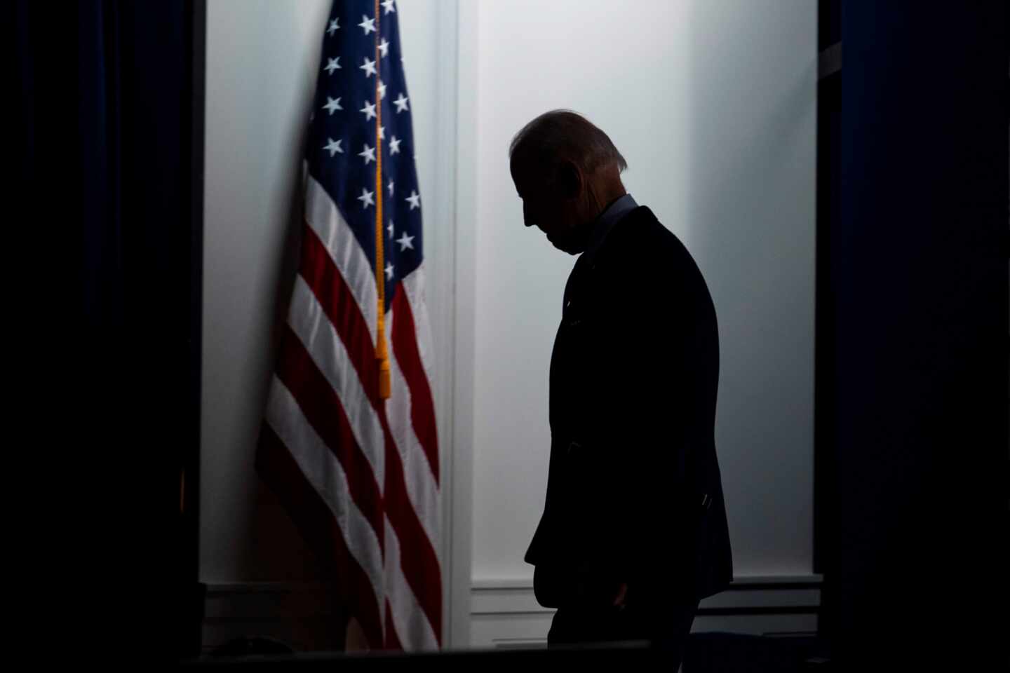 Joe Biden, presidente de EEUU, entre sombras, junto a la bandera de EEUU