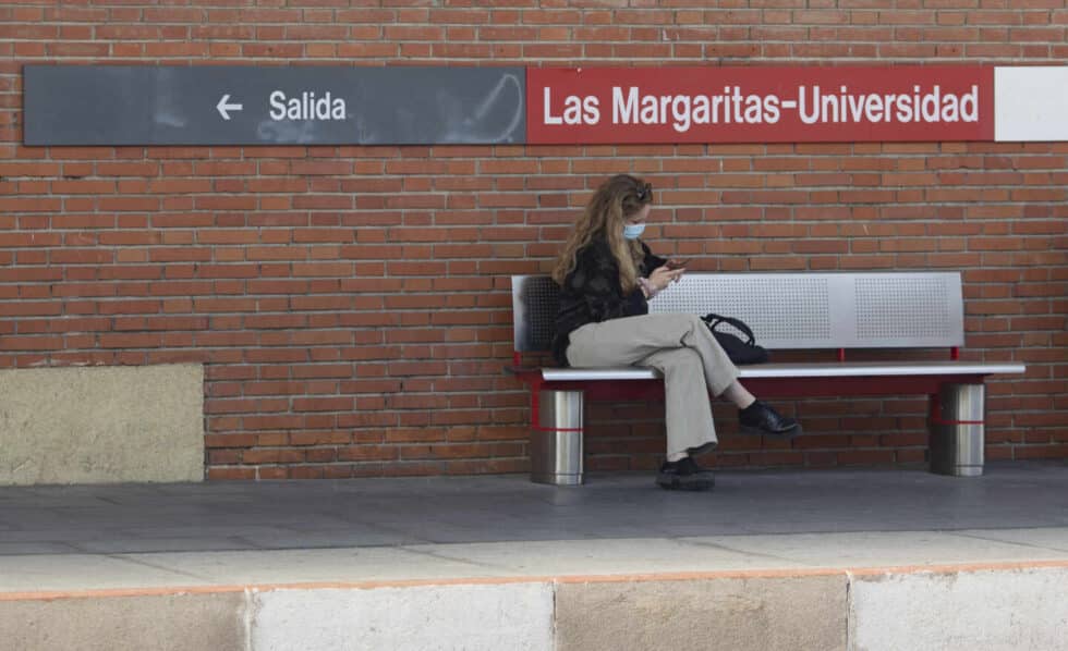 Una estudiante universitaria en un andén de una estación de tren