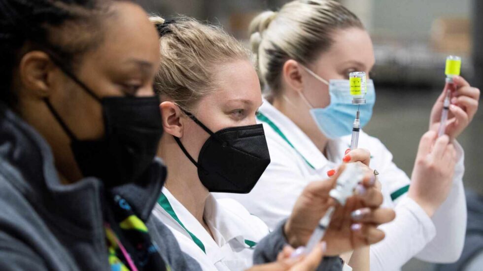Varias enfermeras preparan vacunas en un centro de vacunación masiva en Washington