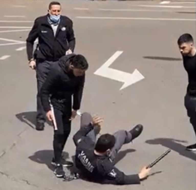 Un vigilante de seguridad en el suelo mientras los dos agresores le increpan