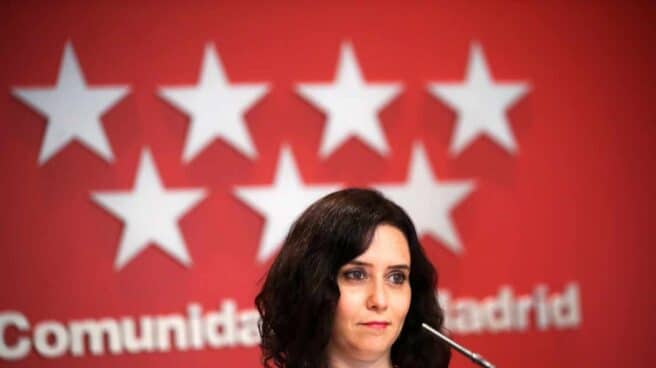 La presidenta de la Comunidad de Madrid, Isabel Díaz Ayuso, delante de una bandera de la Comunidad de Madrid.
