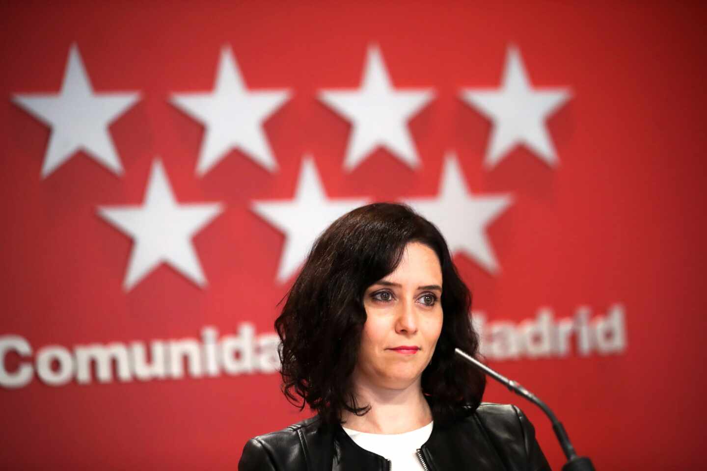 La presidenta de la Comunidad de Madrid, Isabel Díaz Ayuso, delante de una bandera de la Comunidad de Madrid.