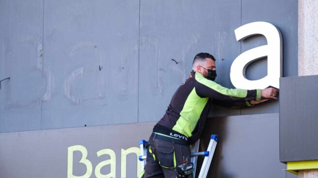 Un operario desmonta el logo de Bankia en la sede del banco en Logroño
