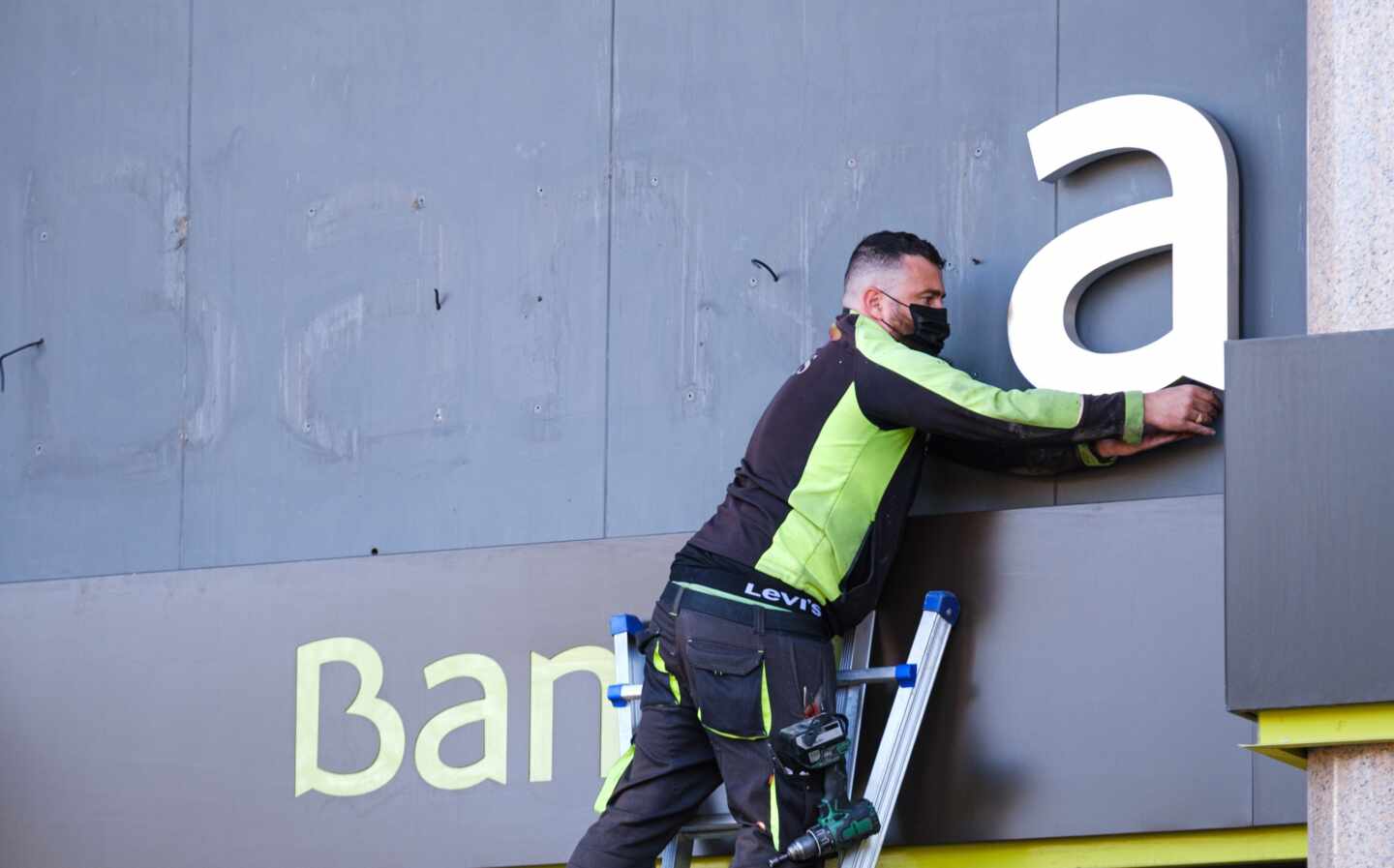 Un operario desmonta el logo de Bankia en la sede del banco en Logroño