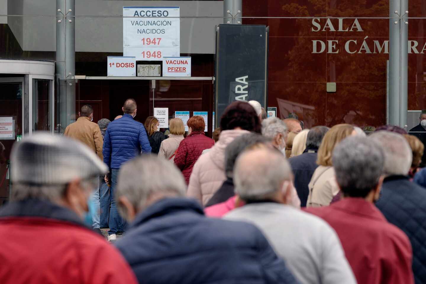 Varias personas citadas para recibir la primera dosis de Pzifer hacen cola a su llegada al centro de vacunación contra la covid-19 montada en la Sála Sinfónica Jesús López Cobos de Valladolid