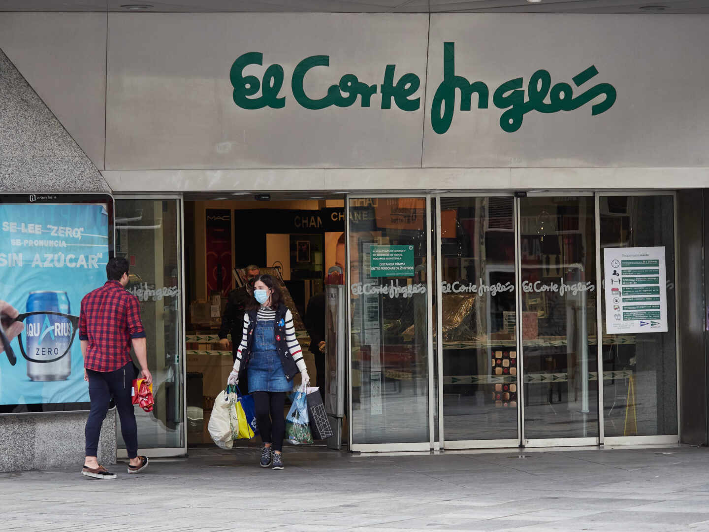 Dos personas se cruzan en la entrada de un centro comercial de El Corte Inglés.