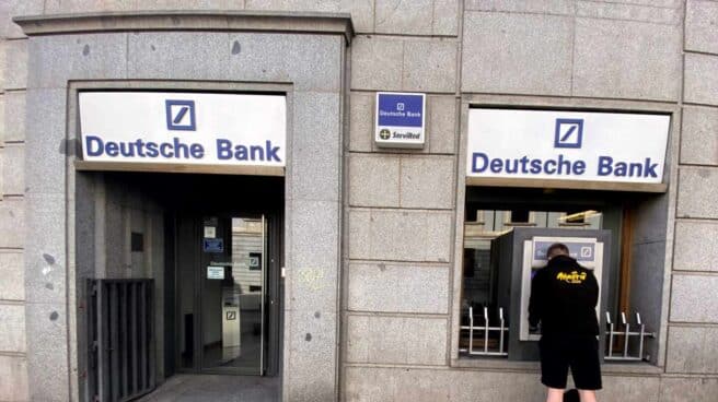 Un hombre retira dinero de un cajero Deutsche Bank.