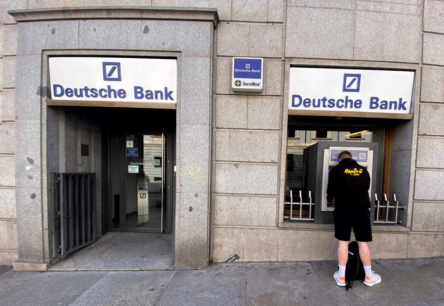 Un hombre retira dinero de un cajero Deutsche Bank.