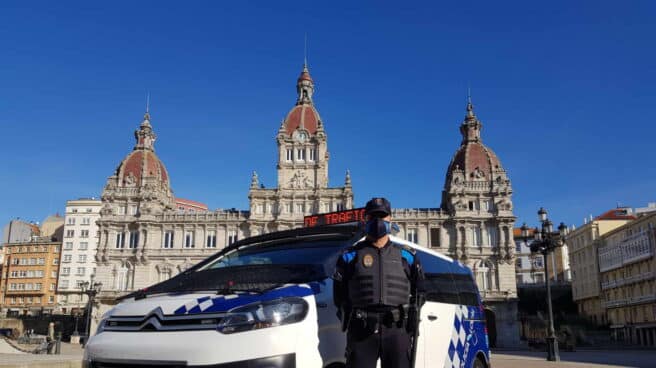 Un agente de la Policía Local de A Coruña delante de un furgón policial