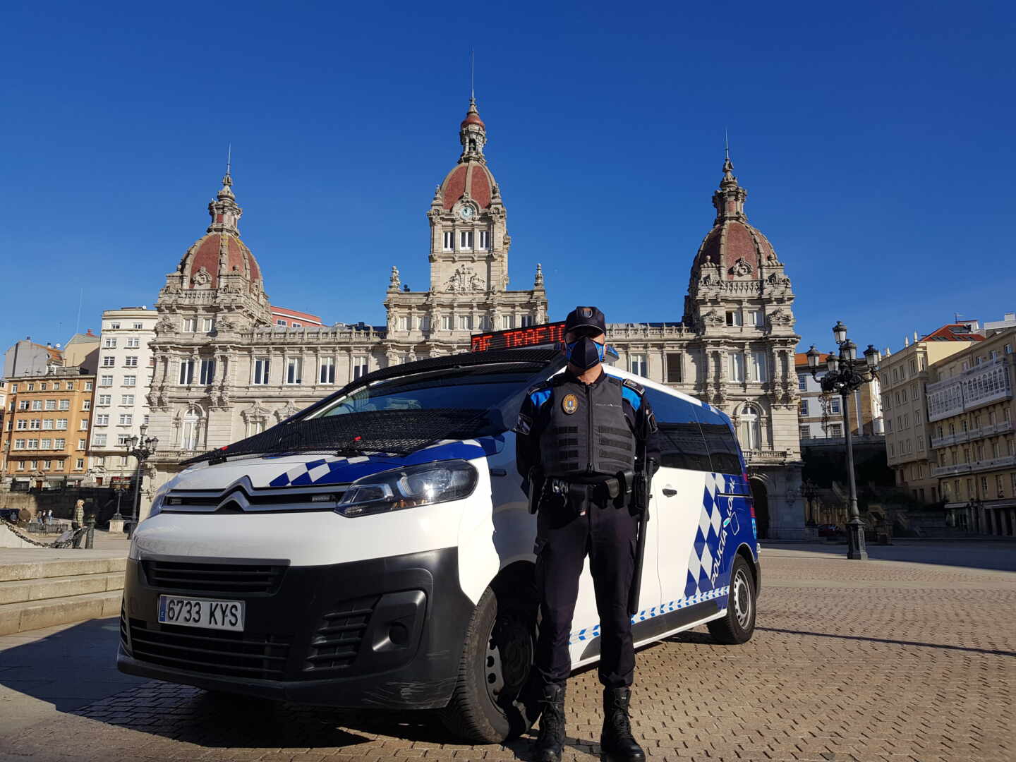 Un agente de la Policía Local de A Coruña delante de un furgón policial