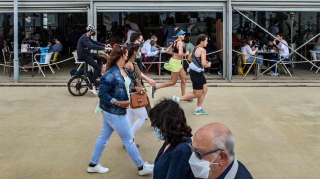 Varias personas pasean frente a un chiringuito del Paseo Marítimo de la Barceloneta hoy domingo, durante el primer día sin toque de queda en Cataluña