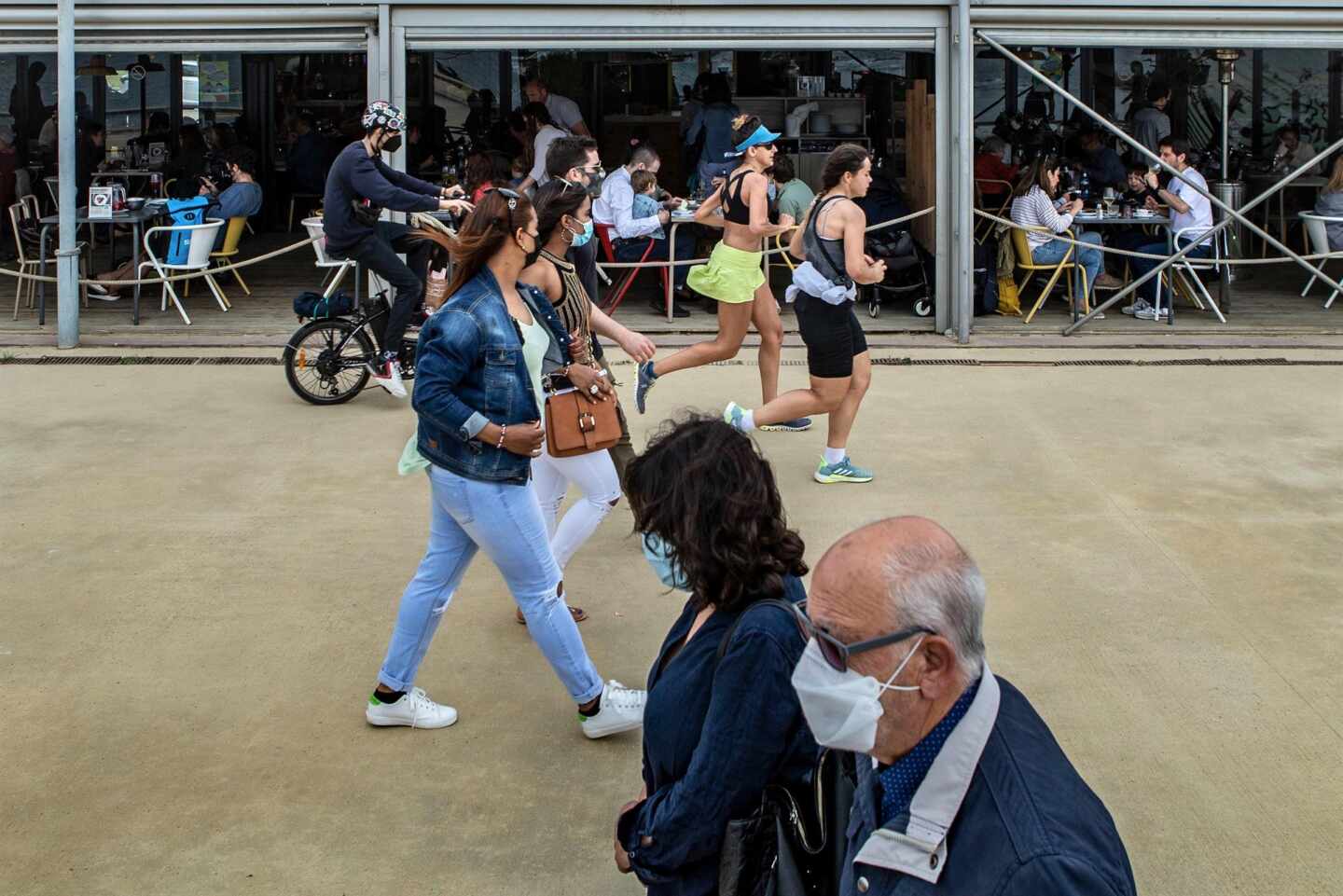 Varias personas pasean frente a un chiringuito del Paseo Marítimo de la Barceloneta hoy domingo, durante el primer día sin toque de queda en Cataluña