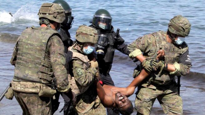 Miembros del Ejército de Tierra trasladan a un migrante que ha logrado cruzar uno de los espigones fronterizos de Ceuta Miembros del Ejército de Tierra trasladan a un migrante que ha logrado cruzar uno de los espigones fronterizos de Ceuta