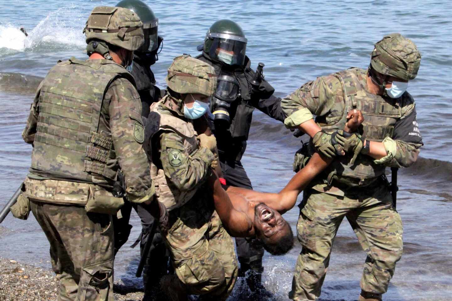 Miembros del Ejército de Tierra trasladan a un migrante que ha logrado cruzar uno de los espigones fronterizos de Ceuta